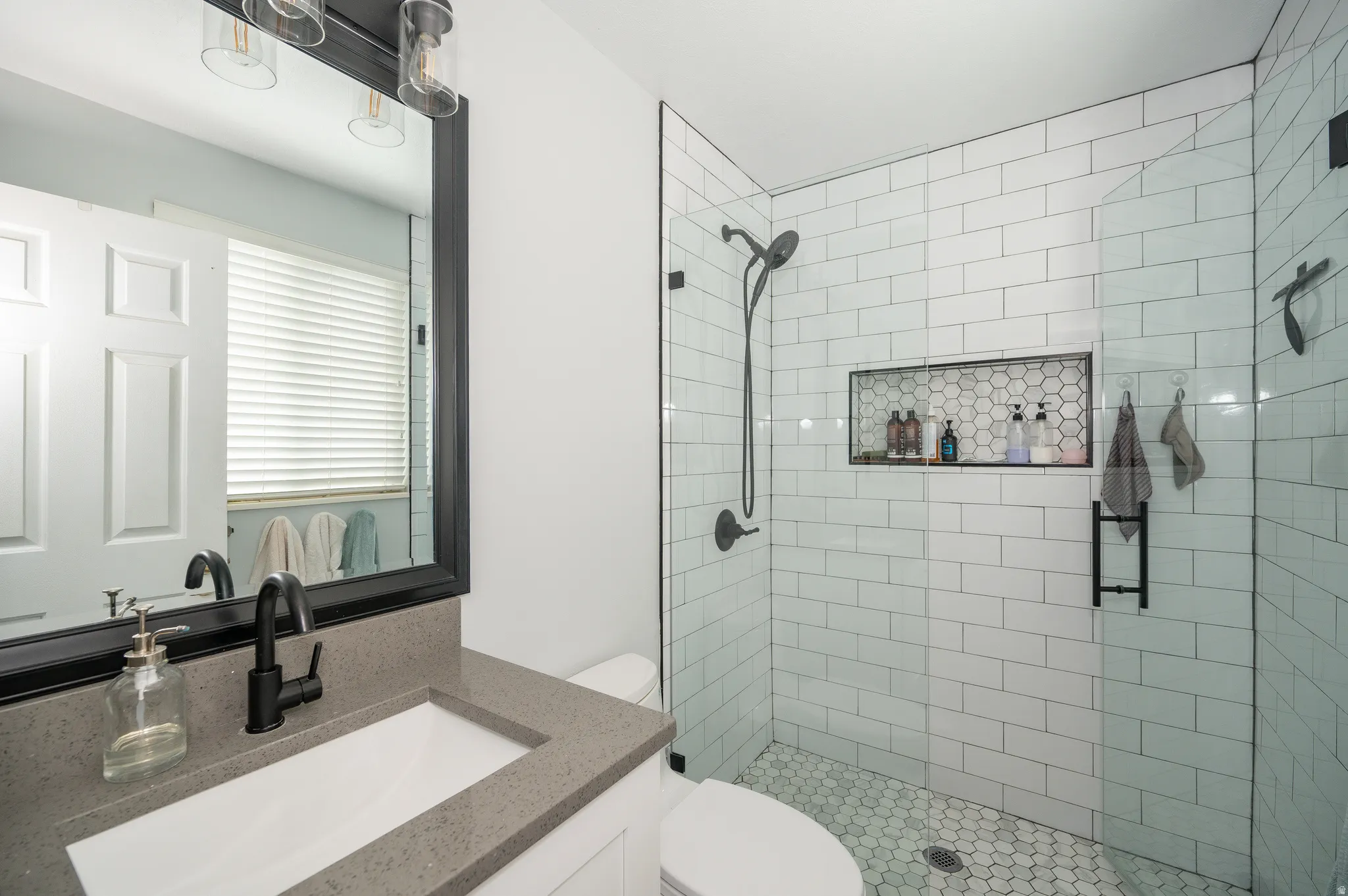 Bathroom featuring a glass-enclosed shower with subway tile surround and a hexagonal tile floor