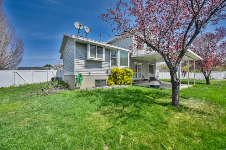 Expansive backyard featuring a covered patio, double French doors, large windows, and a white privacy fence