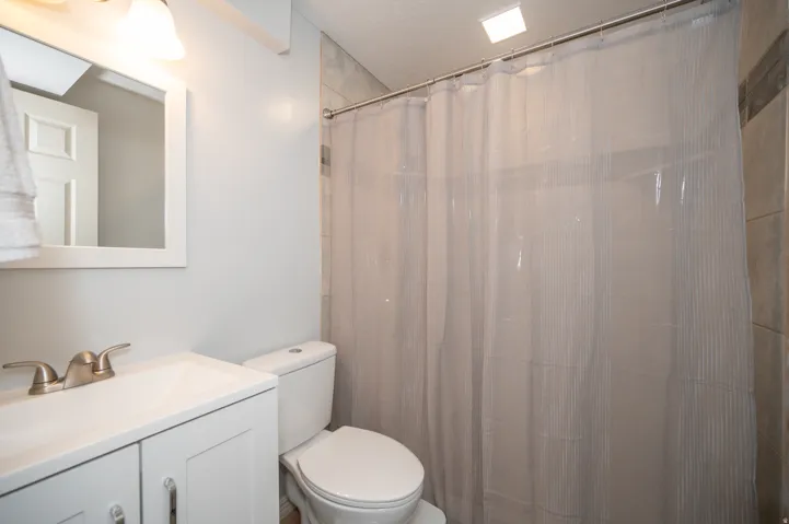 Bathroom featuring a white vanity with integrated sink, brushed nickel faucet, wall-mounted mirror, and a toilet