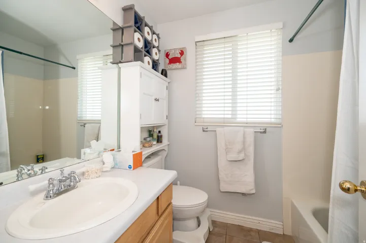 Bathroom featuring a vanity with an integrated sink, a large wall mirror, and a window with blinds