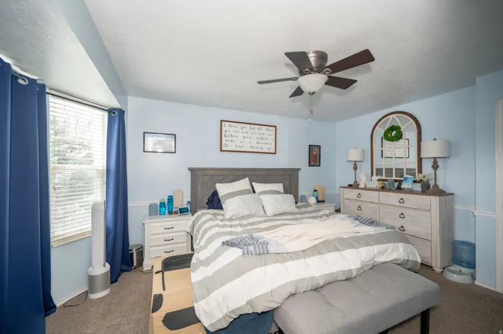 Bedroom featuring a ceiling fan with integrated lighting, a window with blinds, and carpeted flooring