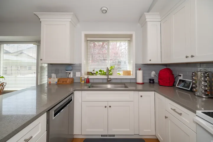 Contemporary kitchen featuring white shaker cabinetry, grey subway tile backsplash, and light gray countertops
