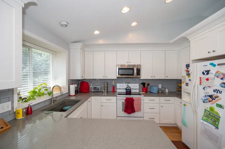 Kitchen featuring white cabinetry, gray subway tile backsplash, light-toned countertops, a built-in microwave, and recessed lighting