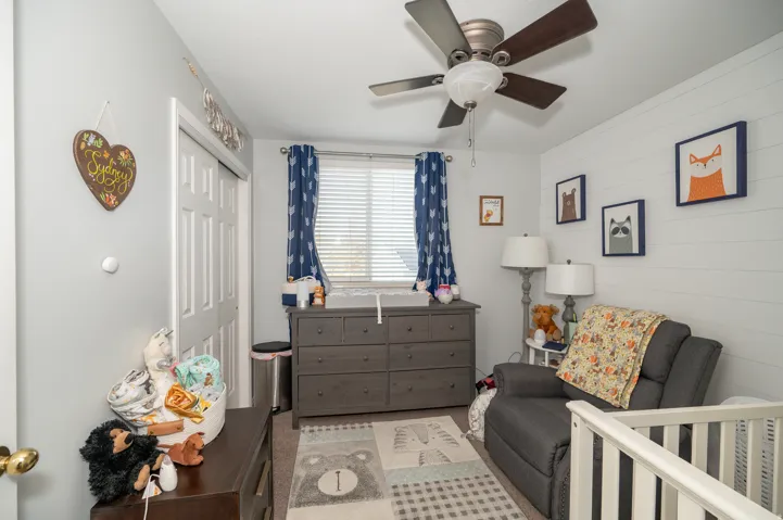 Room featuring a ceiling fan with integrated lighting, a window with blinds, and white shiplap accent wall