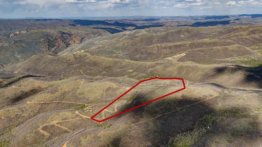 Expansive mountain property featuring varied terrain, a defined parcel boundary, and broad vistas of distant hills