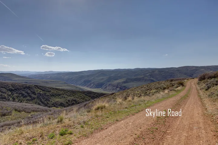 Expansive natural landscape featuring a winding dirt road and distant mountain ranges