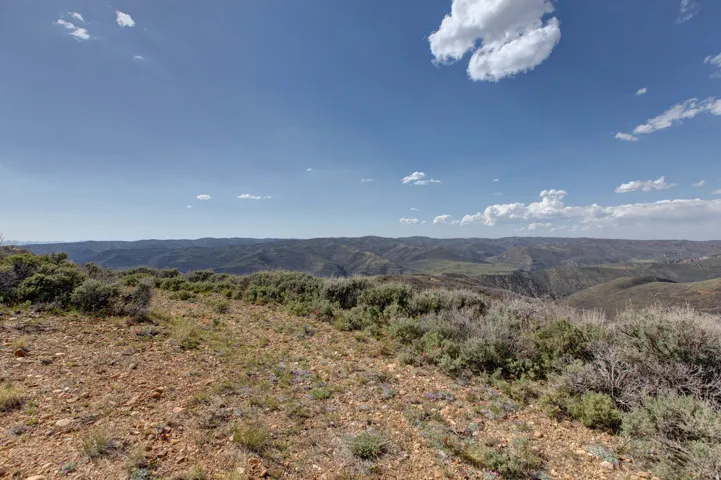 Expansive natural landscape with rolling hills and distant mountains under a clear blue sky