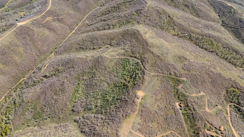 Expansive mountain terrain featuring natural vegetation and winding dirt roads
