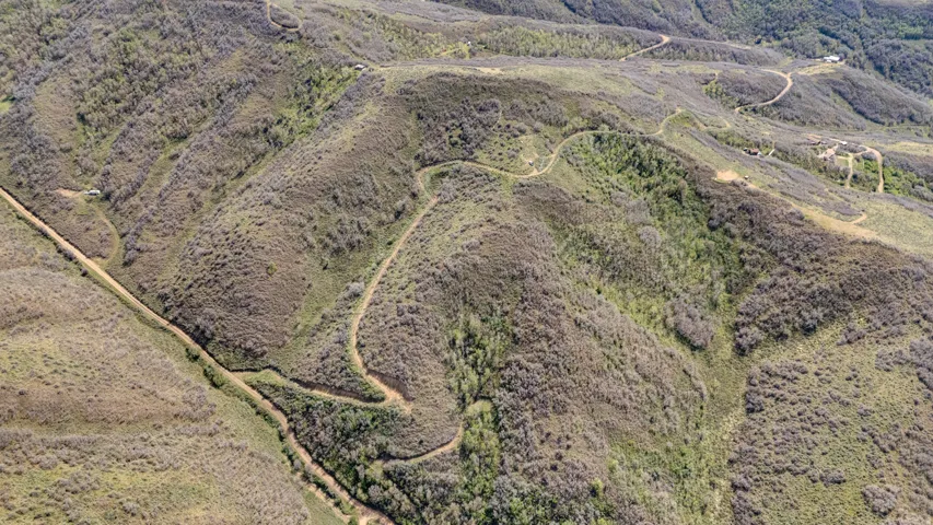 Expansive hillside terrain featuring natural vegetation and winding unpaved roads