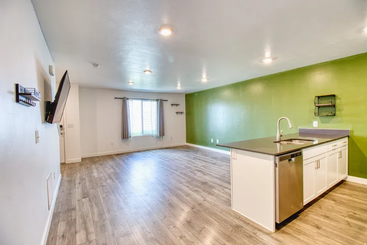 Open-concept living space featuring wood-finish flooring, recessed lighting, and an accent wall