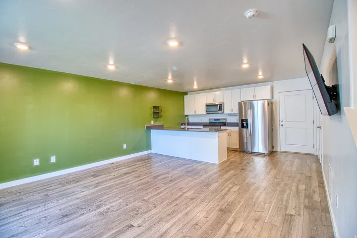 Open-concept living space featuring wood-finish flooring, recessed lighting, and a vibrant accent wall