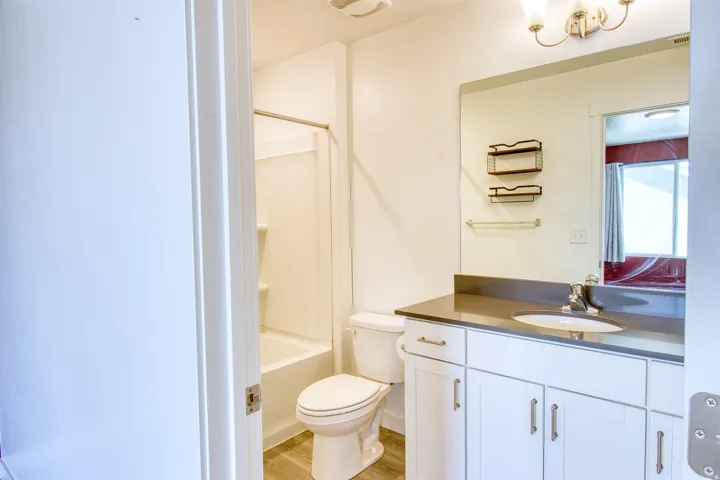 Bathroom featuring a white vanity with integrated sink, dark countertop, and large wall-mounted mirror