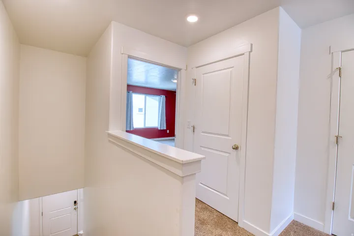 Upper-level hallway featuring a recessed light, two panel doors, and neutral carpeting