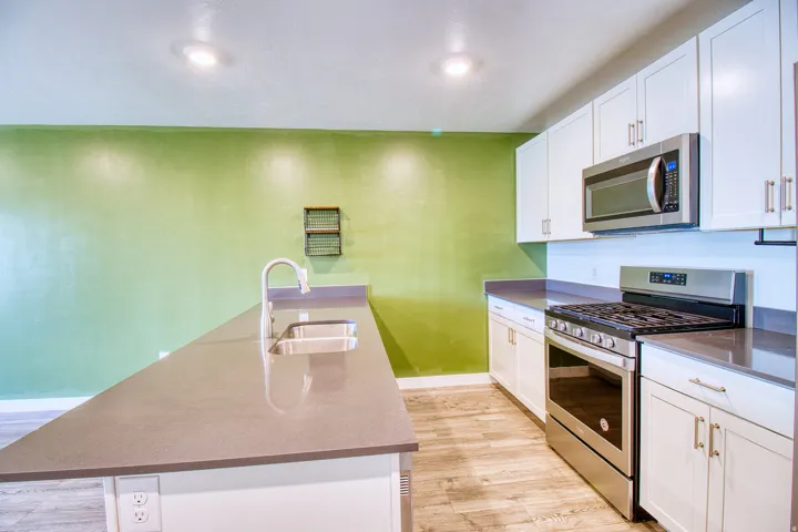 Kitchen featuring a dual-basin sink, a gas range with a stainless steel finish, and white cabinetry with brushed nickel hardware