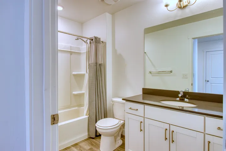 Bathroom featuring a white vanity with shaker-style cabinetry, an integrated sink, and a dark countertop