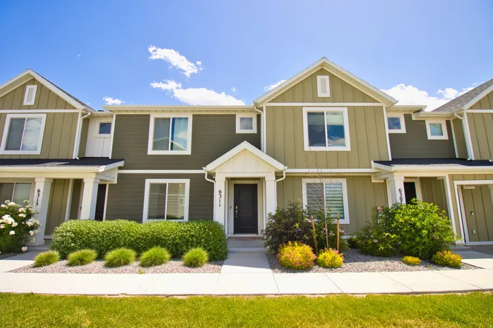 Multi-level townhome exterior featuring an inviting front entry, a well-maintained lawn, and established landscaping