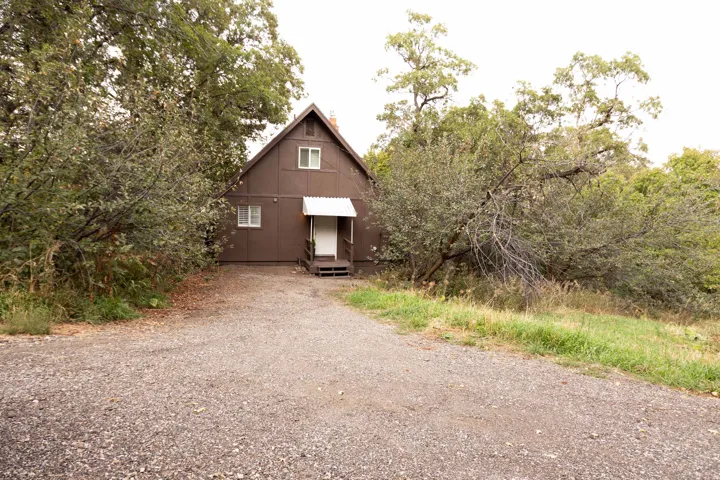 Brown exterior siding home with a white entrance door, covered by a white awning