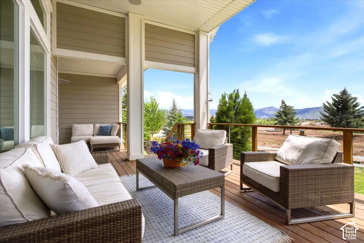 Expansive covered deck featuring a wood-finish floor, wood railing with horizontal metal balusters, and a beige horizontal siding exterior