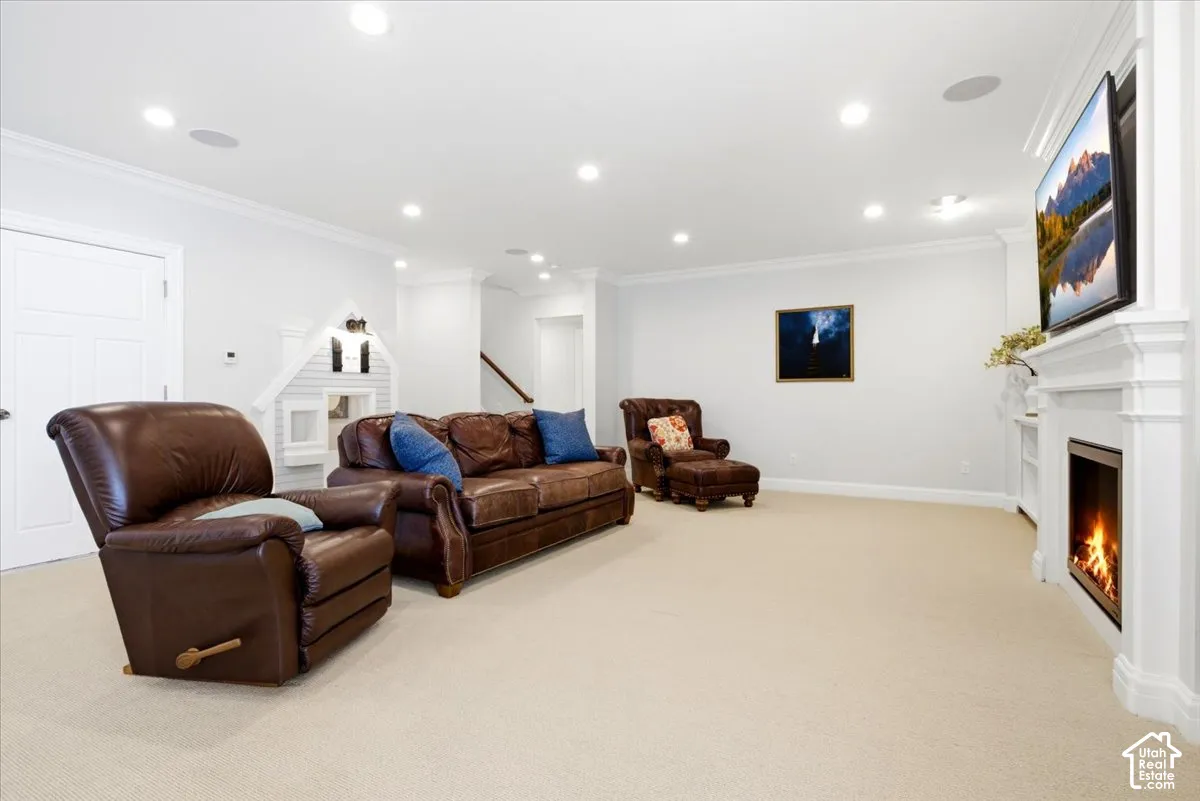 Spacious recreation room featuring recessed lighting, crown molding, a built-in fireplace with a white mantel, and light-toned carpeting