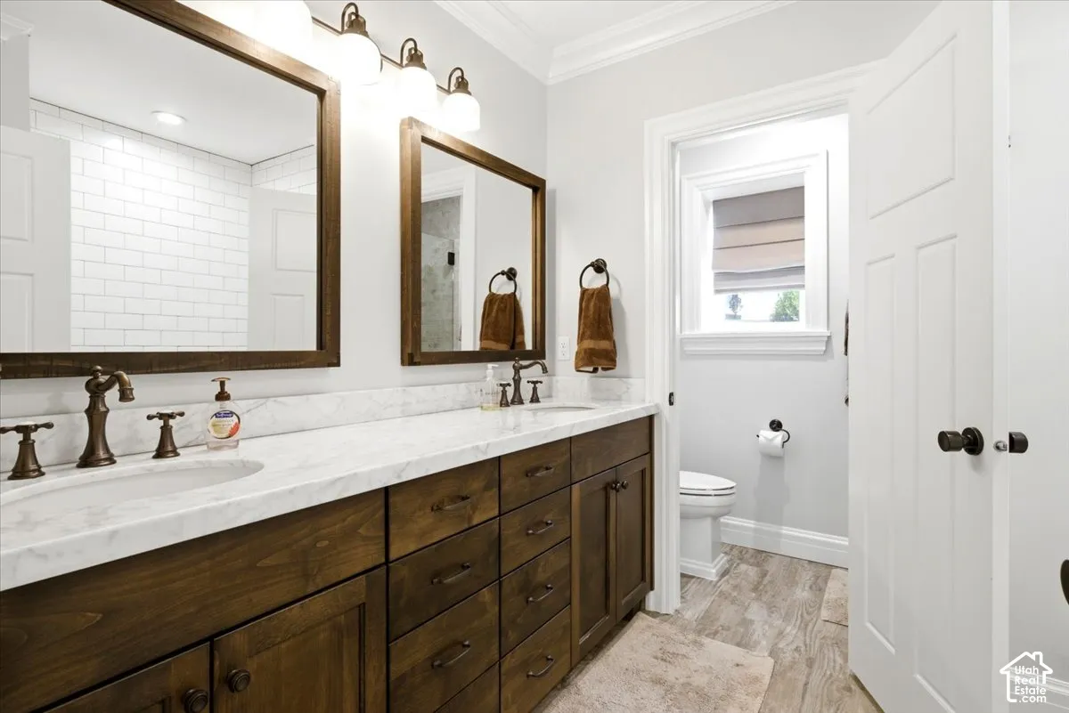 Dual wood-finish vanities with undermount sinks, bronze fixtures, and stone countertops