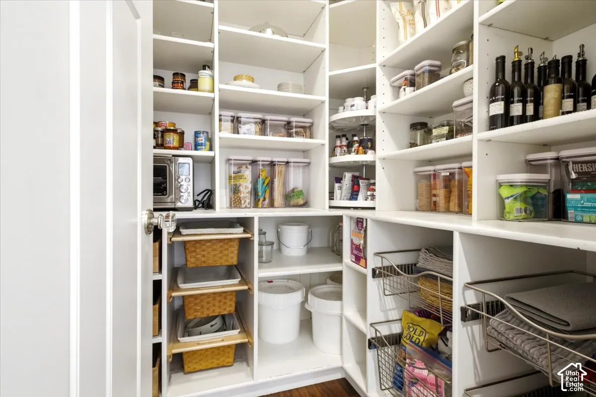 Built-in pantry system featuring white shelving, integrated wire baskets, pull-out storage, and a corner lazy Susan