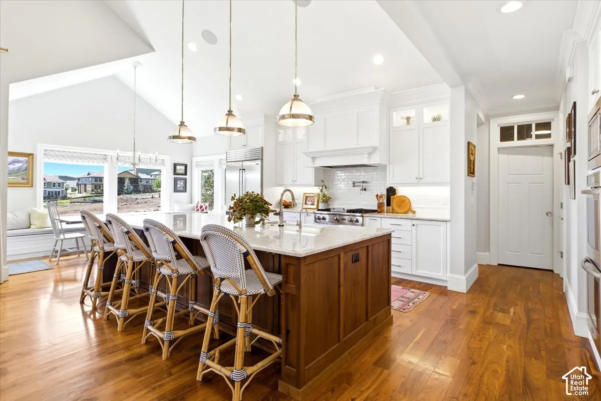 Gourmet kitchen featuring a large central island with seating, stainless steel appliances, and white cabinetry