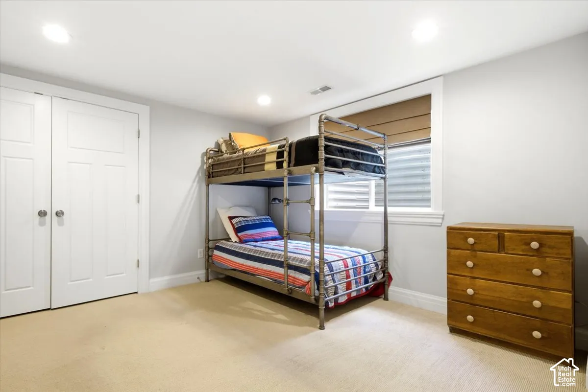 Carpeted room featuring recessed lighting, a window with a blind, and two white panel doors