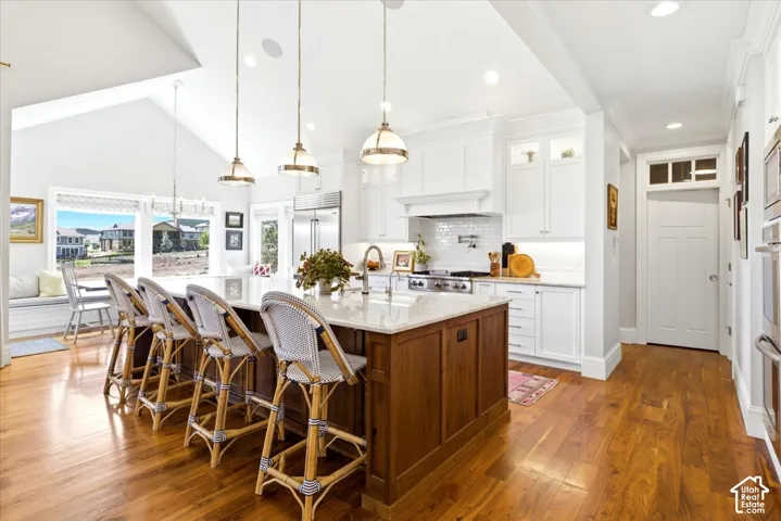 Gourmet kitchen featuring a large central island with seating, stainless steel appliances, and white cabinetry