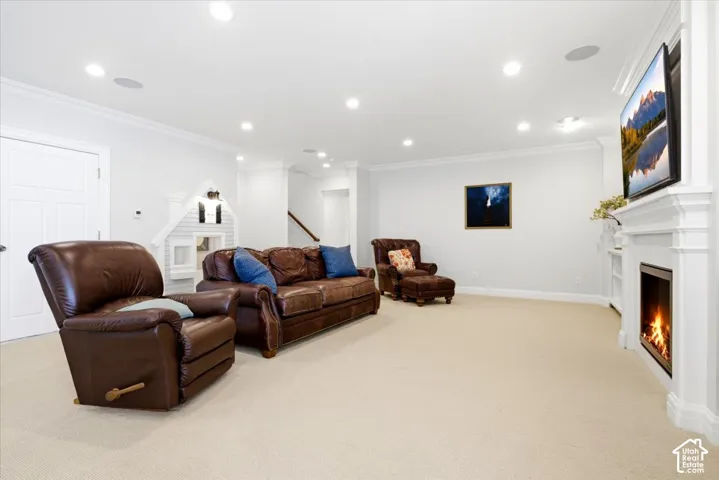 Spacious recreation room featuring recessed lighting, crown molding, a built-in fireplace with a white mantel, and light-toned carpeting