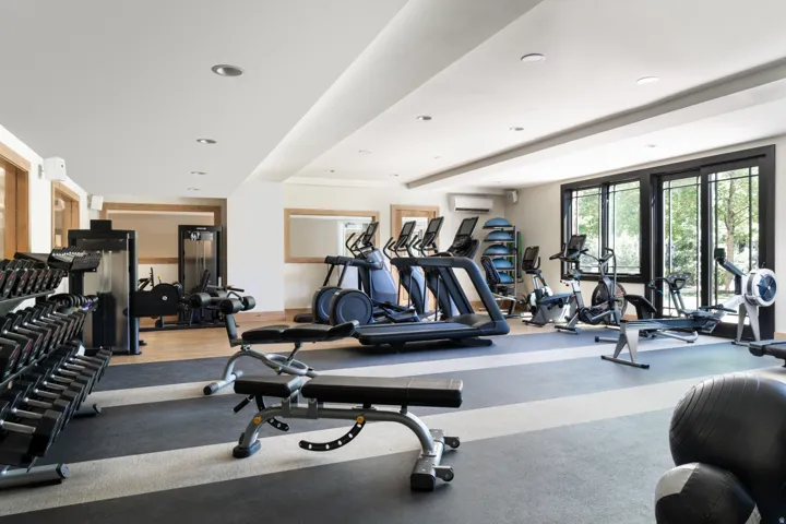 Dedicated fitness space featuring ample natural light, recessed ceiling lighting, a mirrored wall section, and a combination of wood-finish and rubber flooring