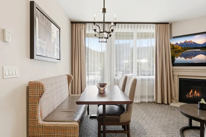 Dining area with a built-in banquette, central chandelier, and large window