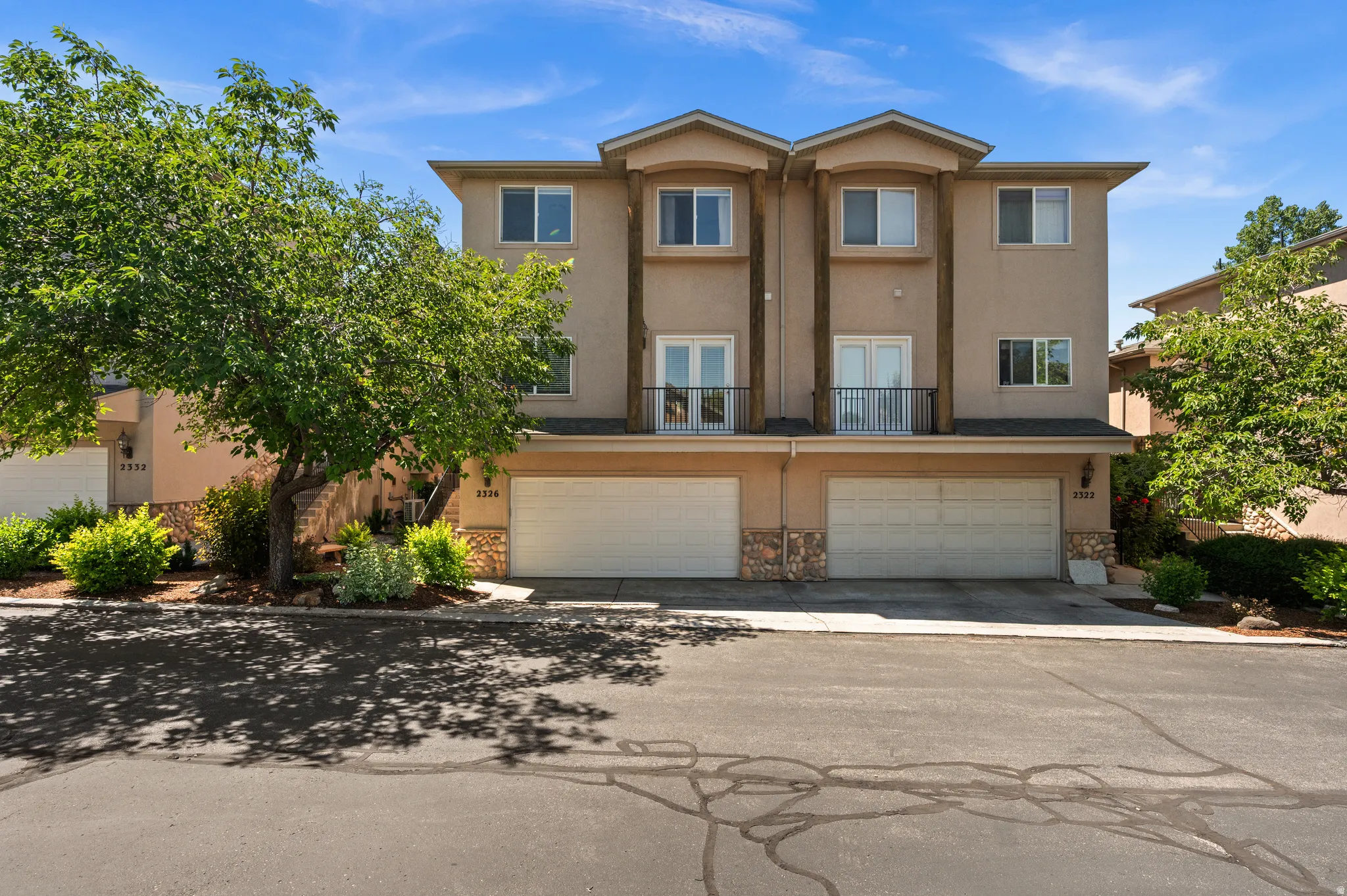 Multi-level townhome exterior featuring stucco siding and stone veneer accents