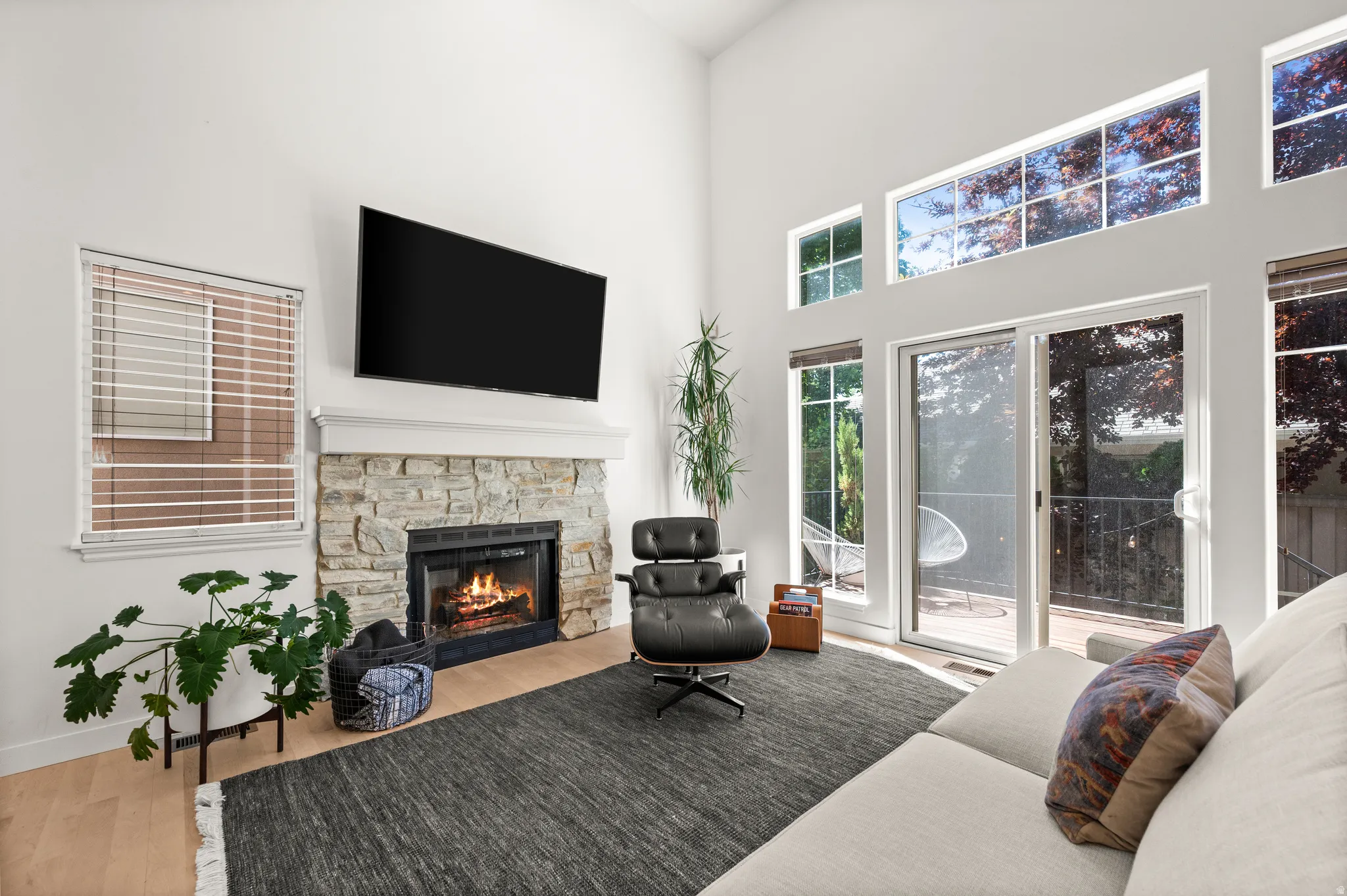 Vaulted living room with southern exposure featuring a stone fireplace with gas insert, and multiple transom windows
