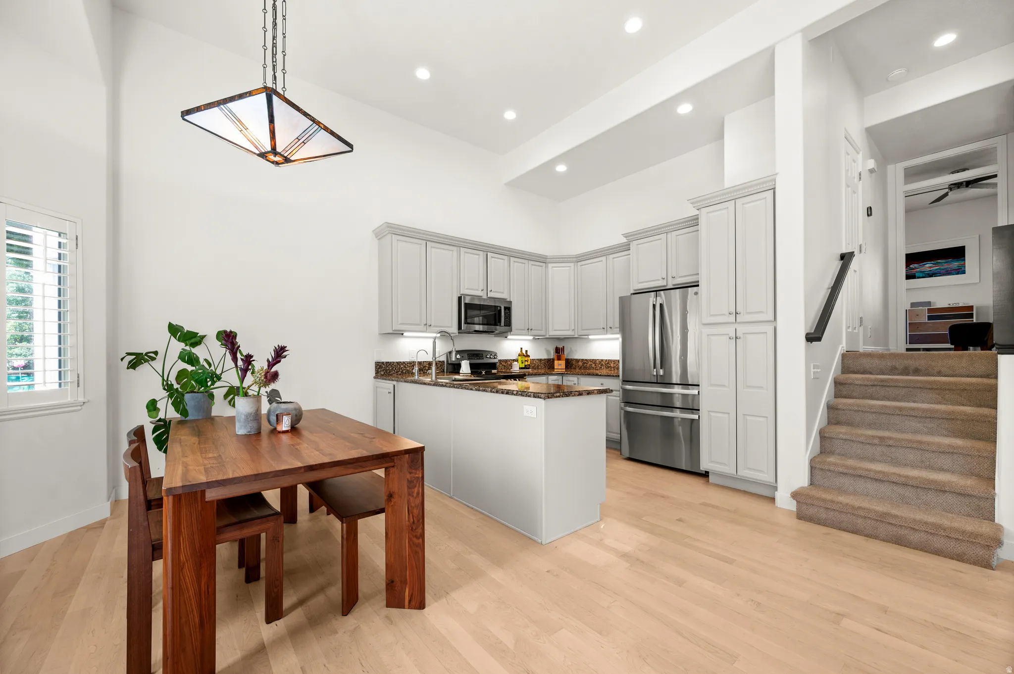 Bright dining room and kitchen with maple hardwood floors, stainless steel appliances, and granite countertops
