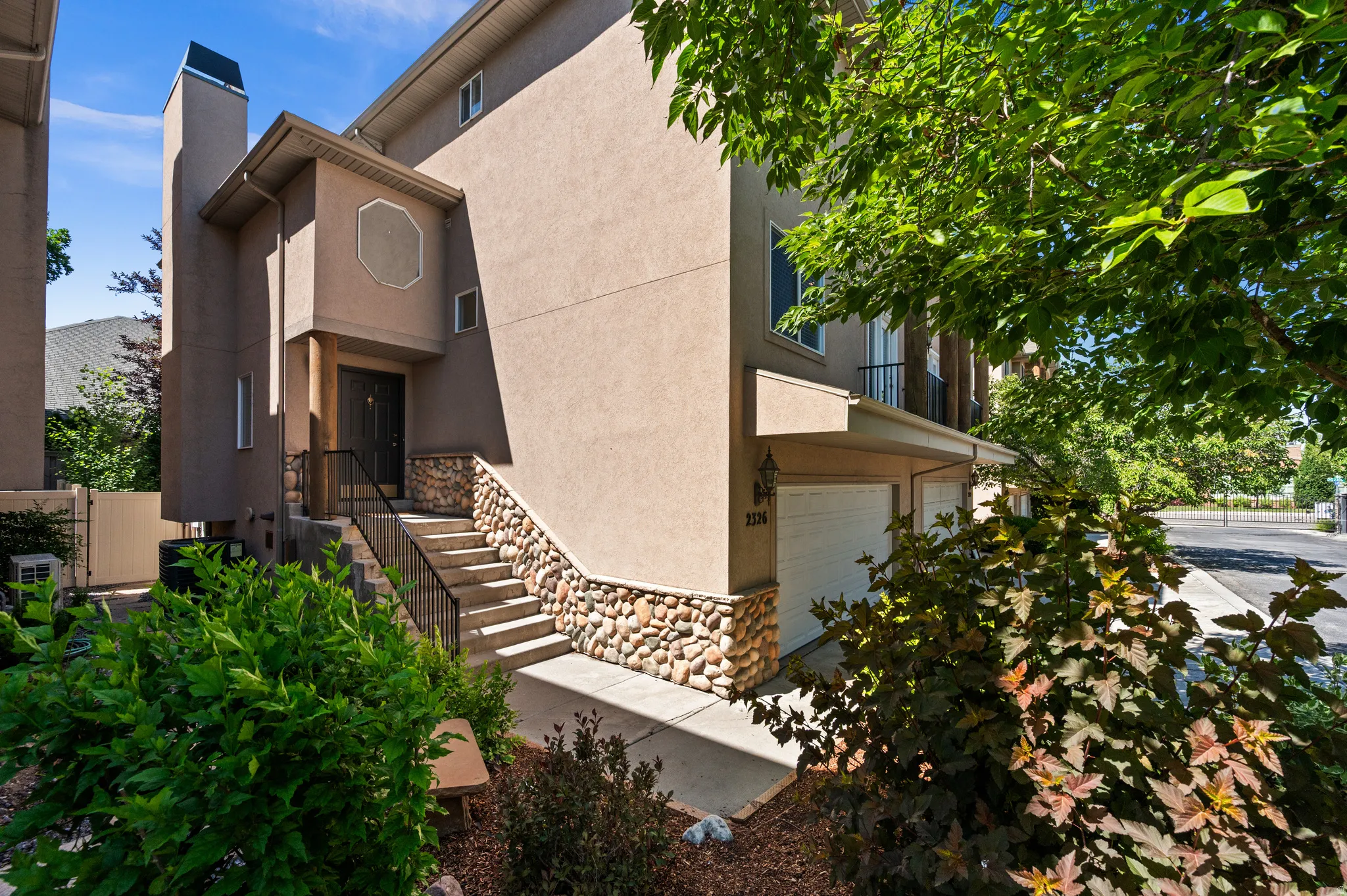 Stucco exterior featuring river rock accents and a two-car garage