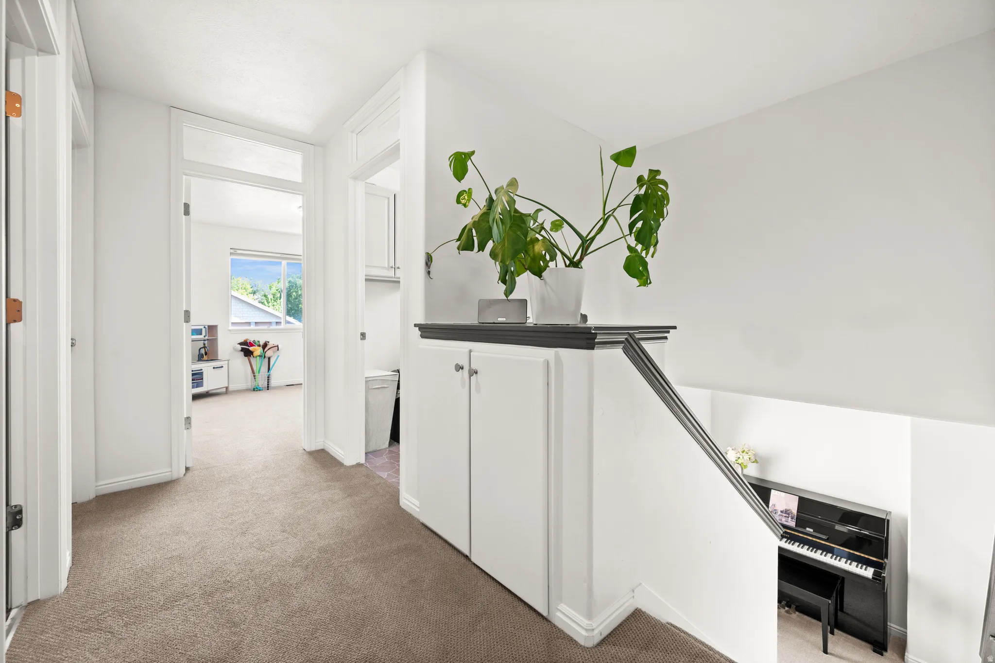 Upper-level hallway featuring neutral carpeting, white painted walls, built-in cabinetry, laundry room