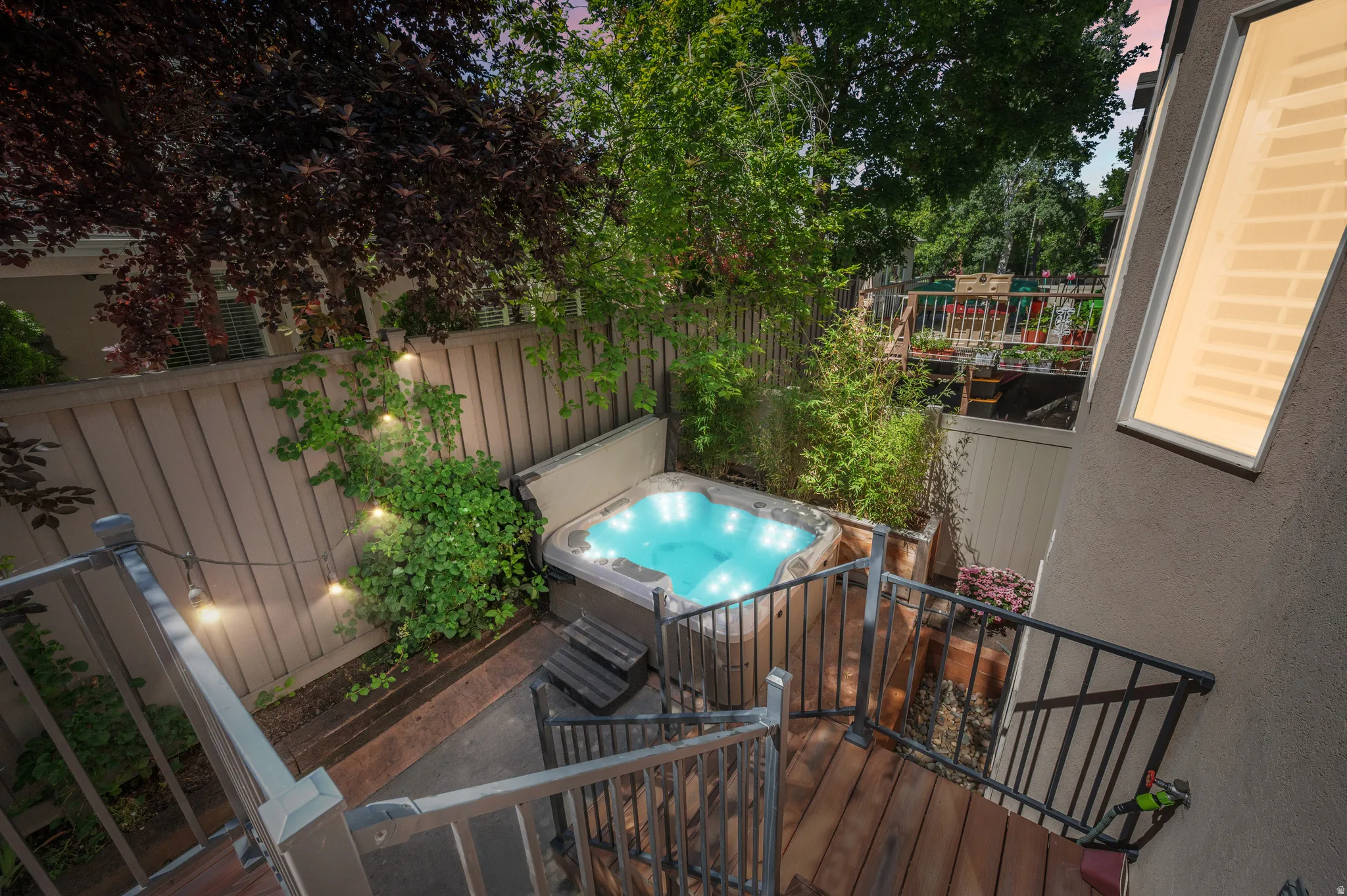 Private outdoor space featuring a hot tub, wood decking, and a slatted privacy fence
