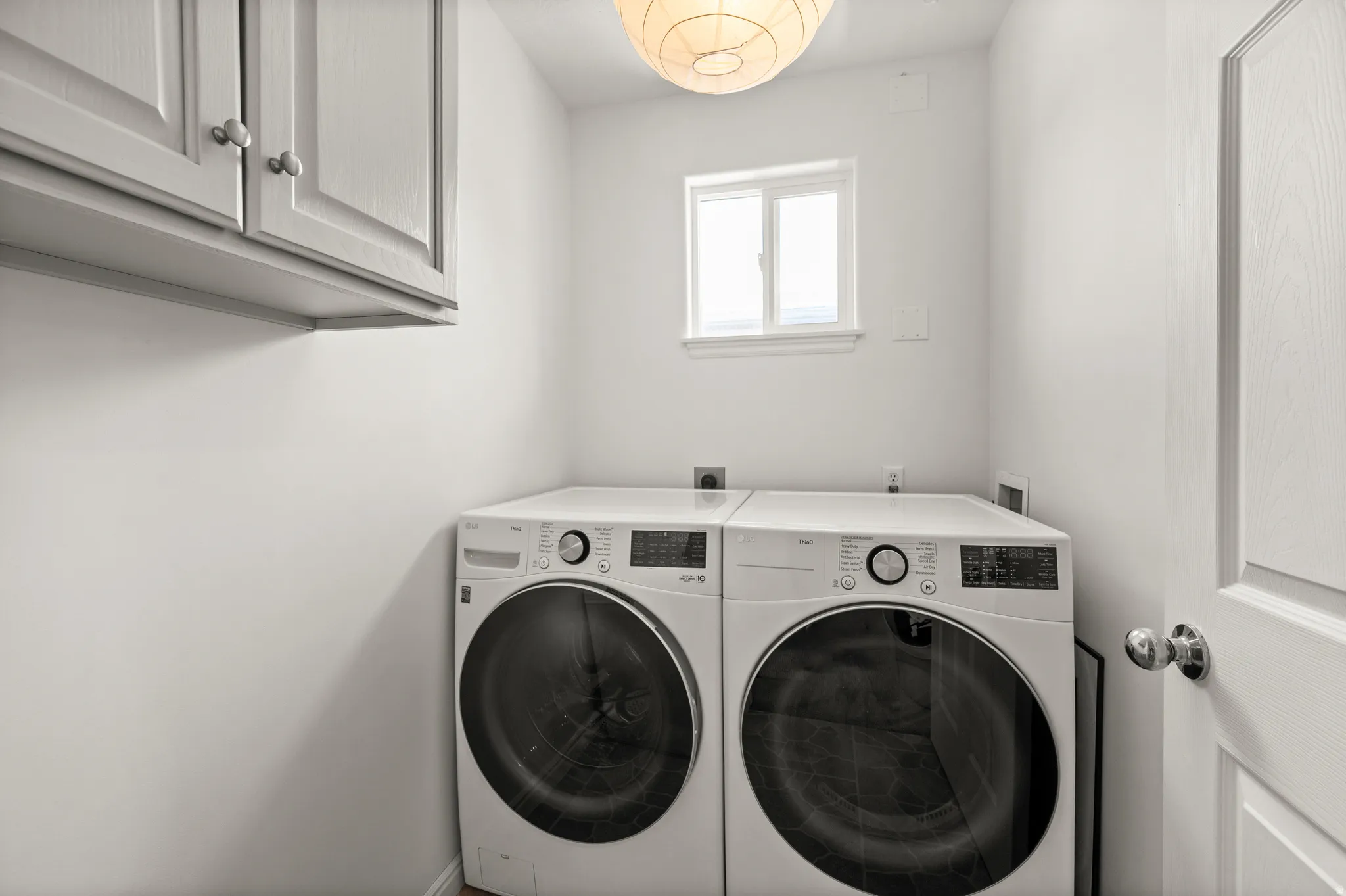 Laundry area featuring included washer and dryer, cabinetry and east facing window