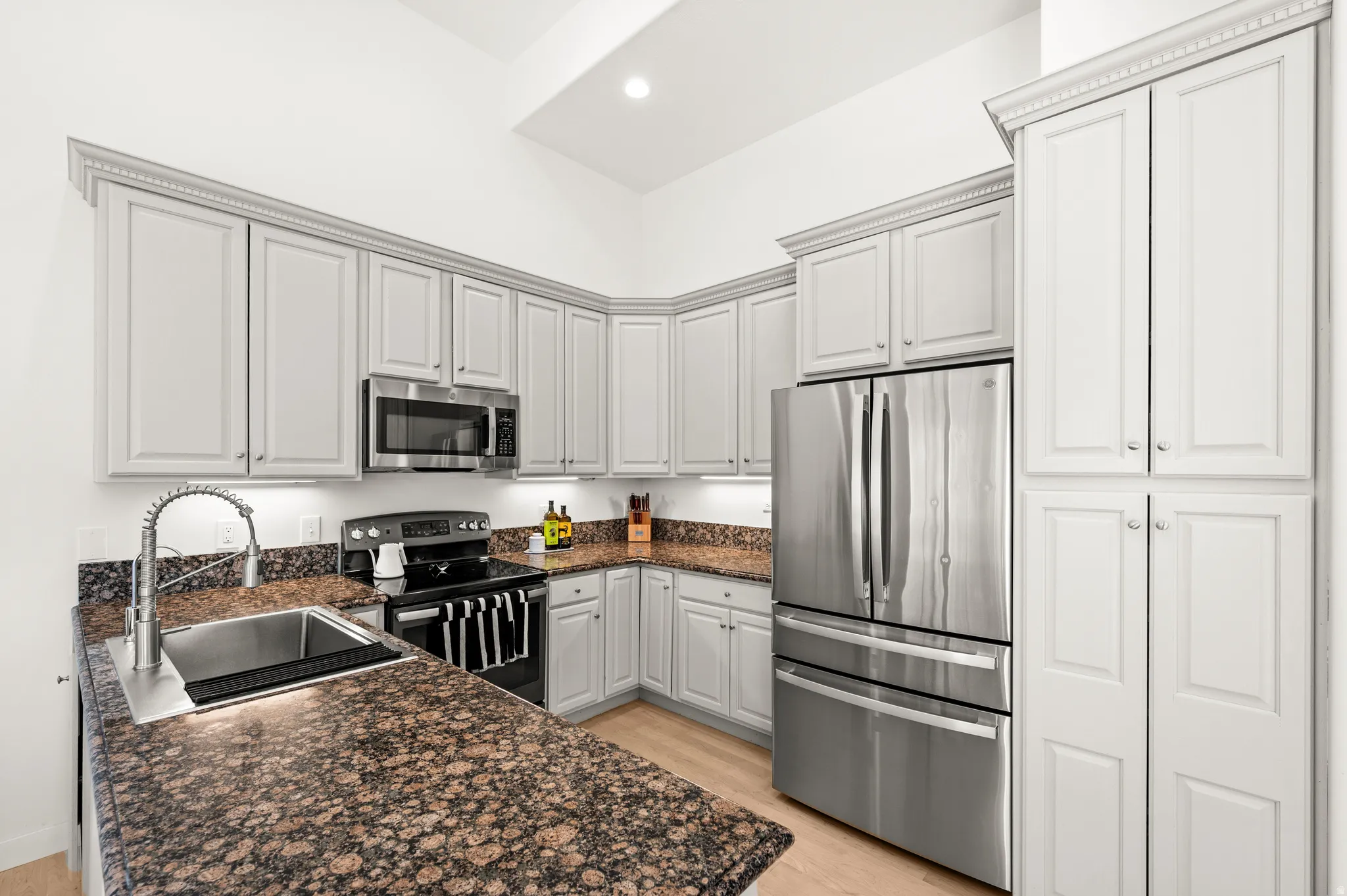 Kitchen featuring light cabinetry with crown molding