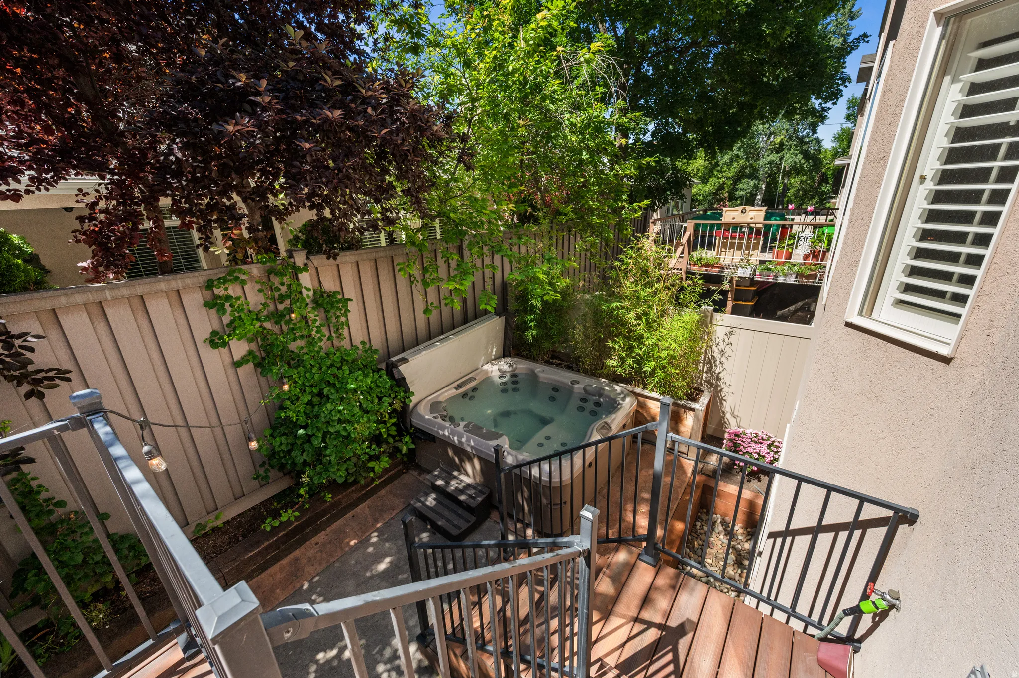 Backyard area featuring a hot tub, patio surrounded by wood fencing and mature landscaping