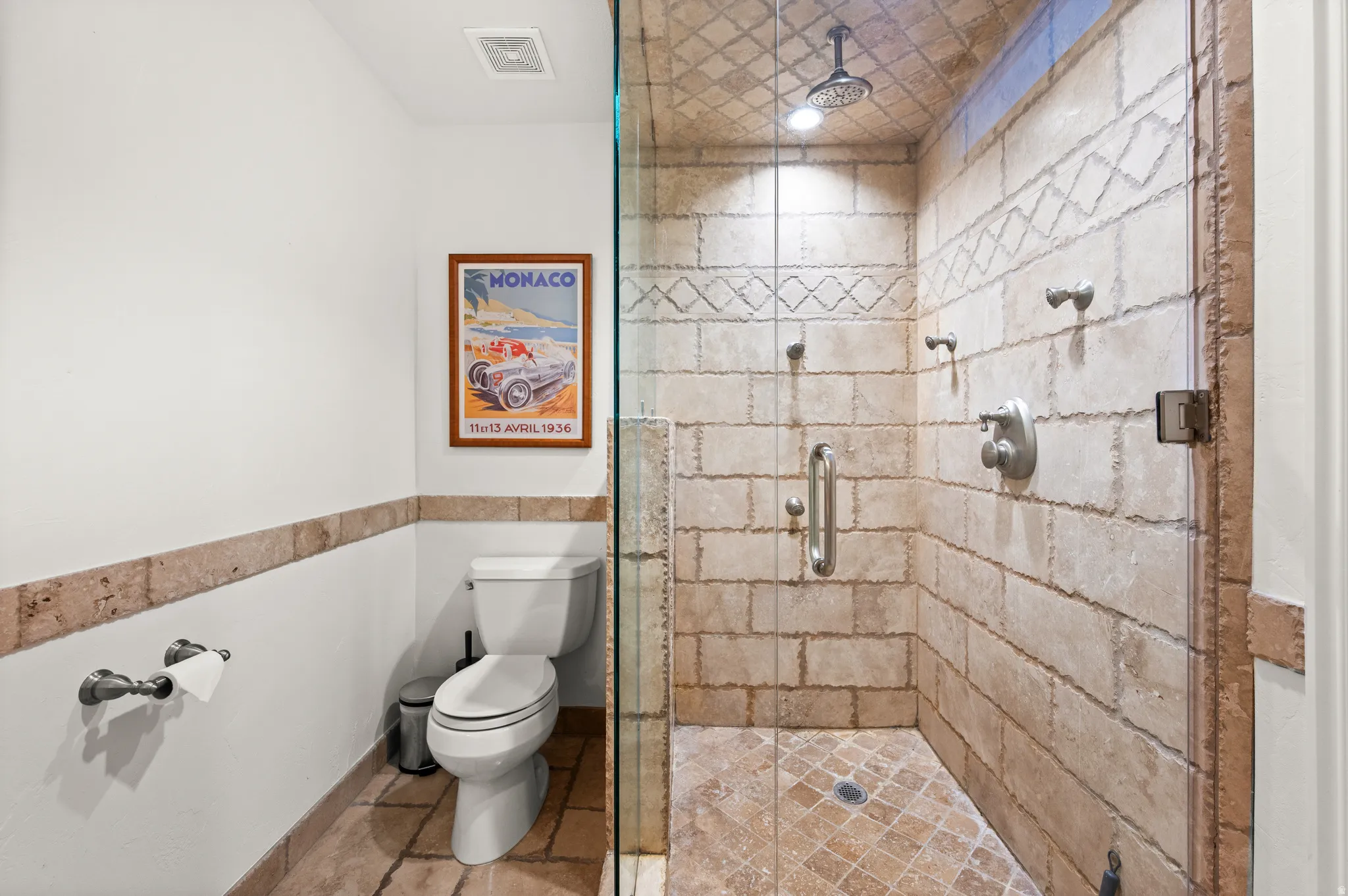 Glass-enclosed shower with full-height stone tile surround and rain shower head