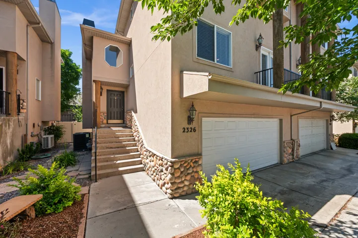 Multi-level stucco exterior featuring stone veneer accents, a prominent entry staircase with handrail, and an octagonal window detail