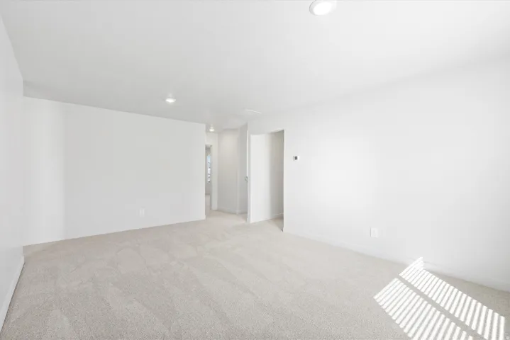 Spacious room with light-toned carpeting and neutral white walls