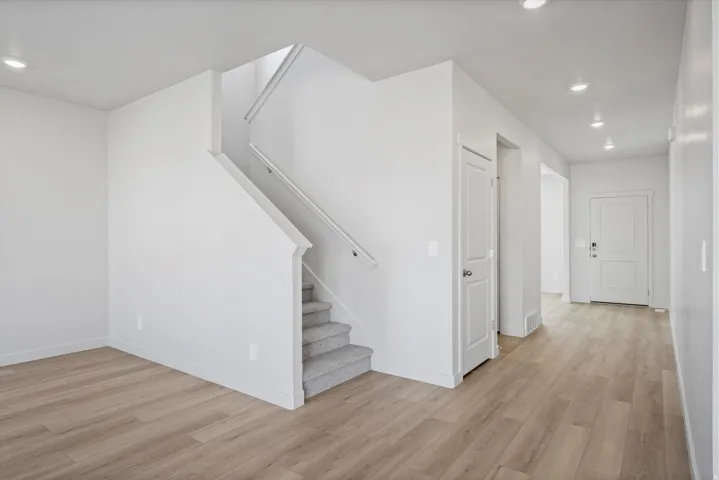 Entryway featuring wood-finish flooring, recessed lighting, and a staircase with carpeted treads and a white railing