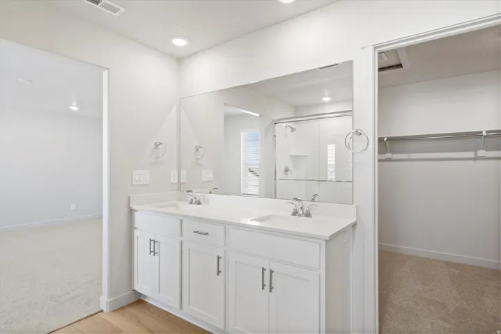 Dual-sink vanity featuring a white countertop, chrome fixtures, and white shaker-style cabinetry