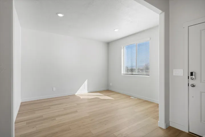 Bright room with wood-finish flooring and a large window featuring horizontal blinds