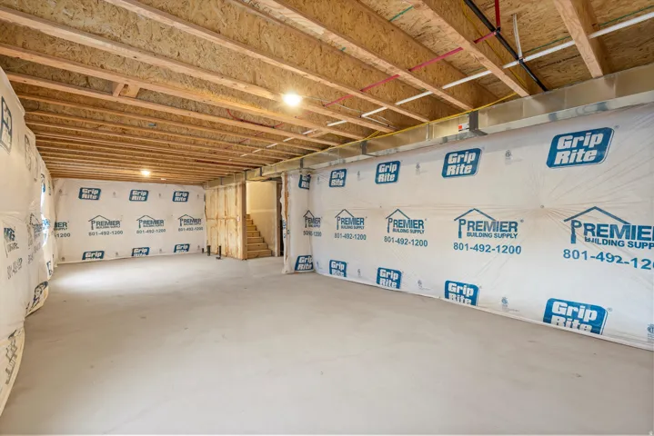Unfinished basement featuring exposed wood joists, concrete flooring, and insulated perimeter walls