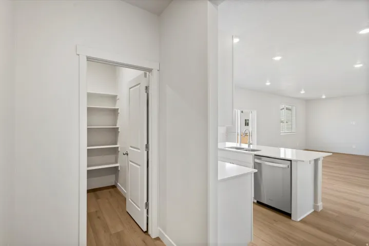 Walk-in pantry with extensive shelving, complemented by light wood-finish flooring throughout