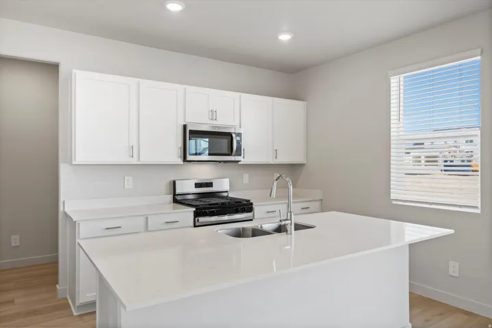 Kitchen with white cabinetry, stainless steel appliances, and a central island featuring a double-basin sink