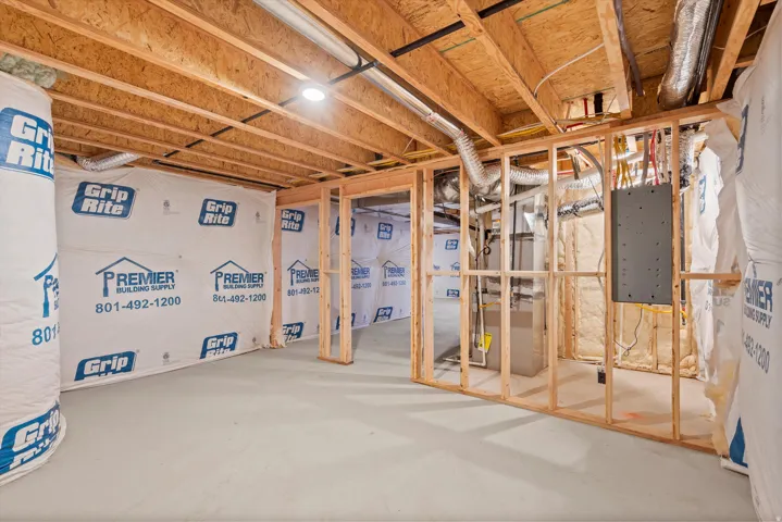 Unfinished basement offering exposed wood joists, concrete flooring, and framed partitioning